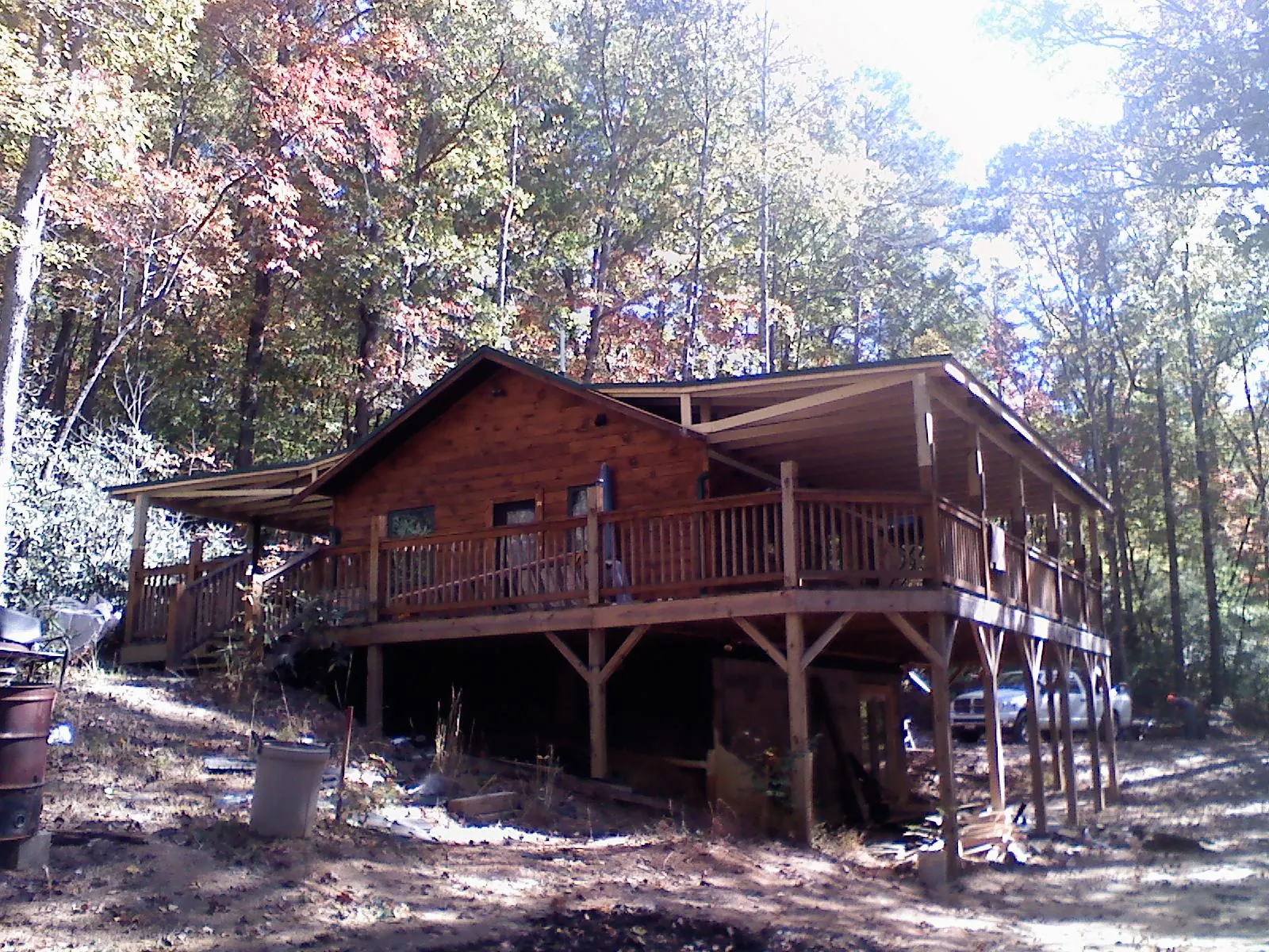 Log cabin with a wraparound porch and metal roof in the fall in North Vernon