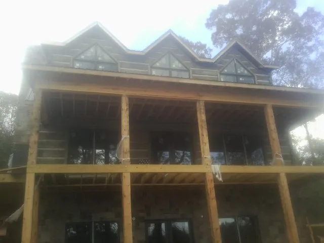 Dormers and porch framing on a large log home under construction — Roof Coating work by our crew in North Vernon