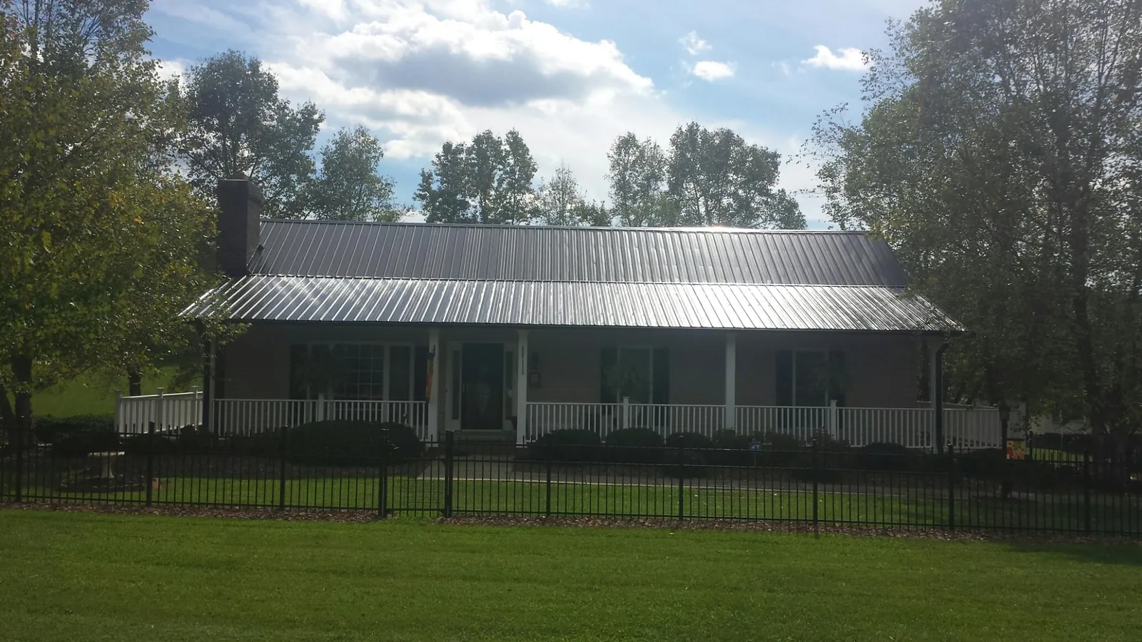 Gray metal roof on a brick ranch with a full width front porch — Gutter Guard Installation work by our crew in North Vernon