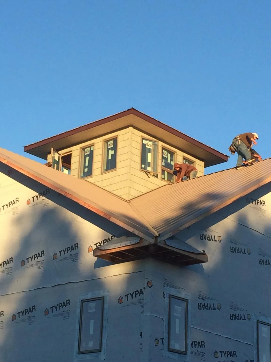 Roofers working around a rooftop cupola on a new metal roof at sunset — Roof Waterproofing in North Vernon by Roofing Brothers